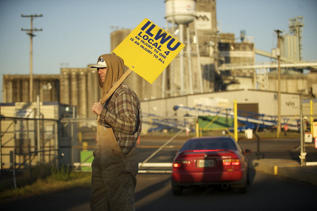 An International Longshore and Warehouse Union local 4 supporter holds a sign outside the main gate to United Grain as a vehicle enters May 1 in Vancouver.