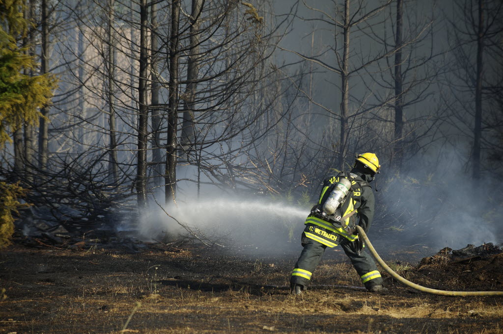 A firefighter works to extinguish a fast-moving fire Tuesday afternoon near the Prairie View Apartments.