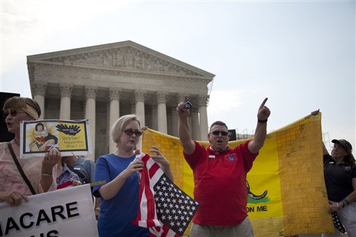 Demonstrators stand outside the Supreme Court in Washington, Monday, June 25, 2012.