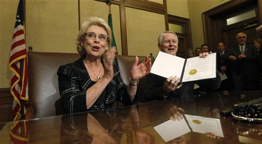 Gov. Chris Gregoire, left, applauds as Secretary of State Sam Reed holds up the signed certification of Referendum 74, a citizen-passed measure that legalizes same-sex marriage in the state Wednesday in Olympia. Gregoire and Reed both signed the document at the signing ceremony, which allows gay couples to marry beginning Dec.