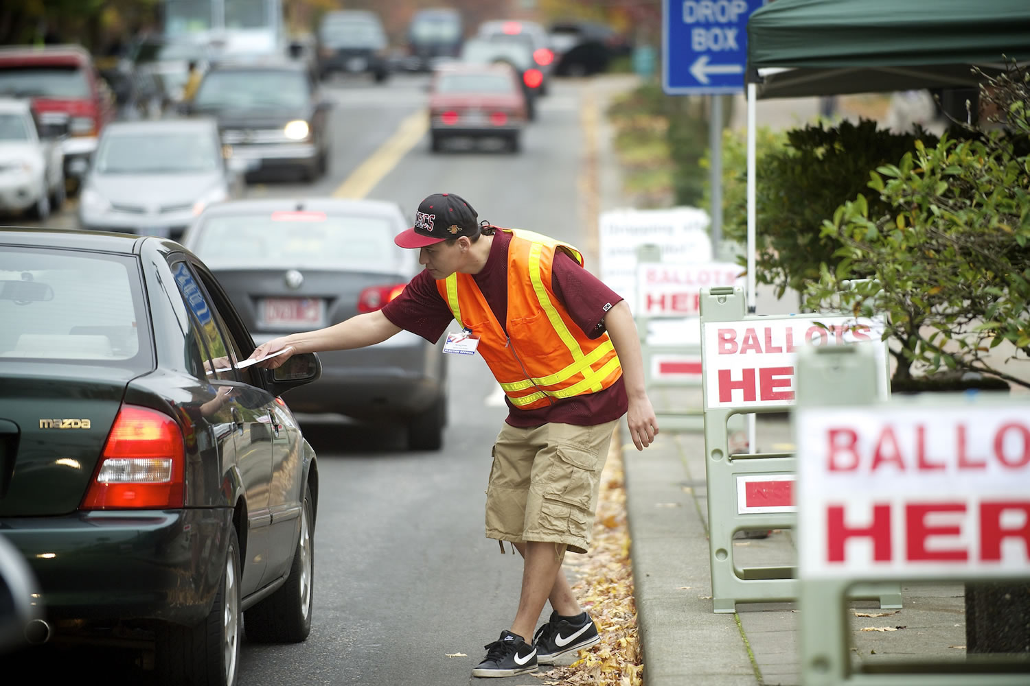 Clark County elections official Miguel Rivera takes ballots from motorists outside the Clark County Elections office Tuesday.
