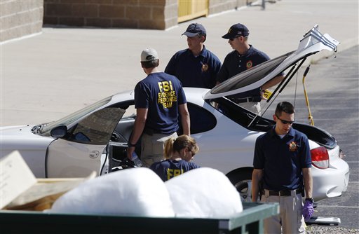 Investigators examine a vehicle parked outside a back exit at the Century 16 movie theater east of the Aurora Mall in Aurora, Colo. today. A gunman in a gas mask barged into a crowded Denver-area theater during a midnight showing of the Batman movie, hurled a gas canister and then opened fire in one of the deadliest mass shootings in recent U.S.