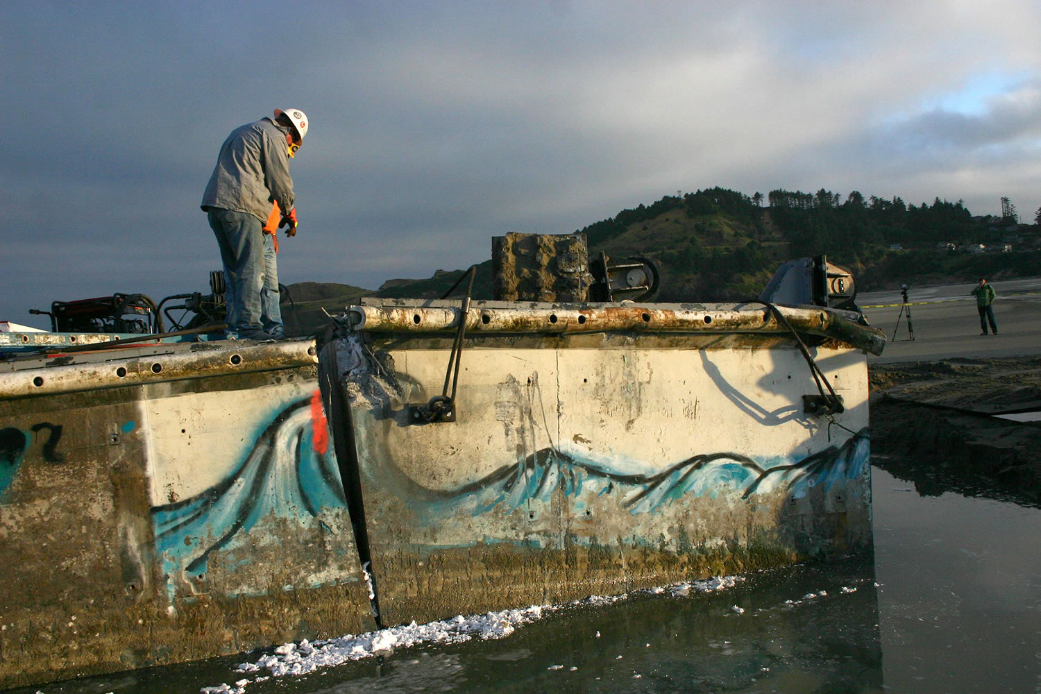 Contractors create a second cut on the dock torn loose by Japan's 2011 tsunami that washed up on Agate Beach near Newport, Ore., in June.