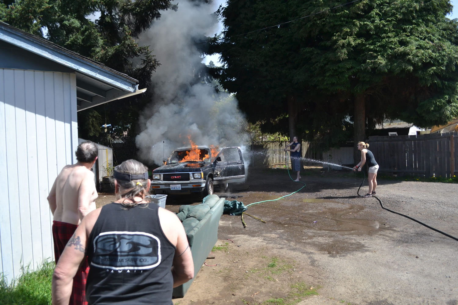 Local residents work to put out the fire that destroyed a vehicle on Thursday, April 25 near East 36th Street and O Street in Vancouver.