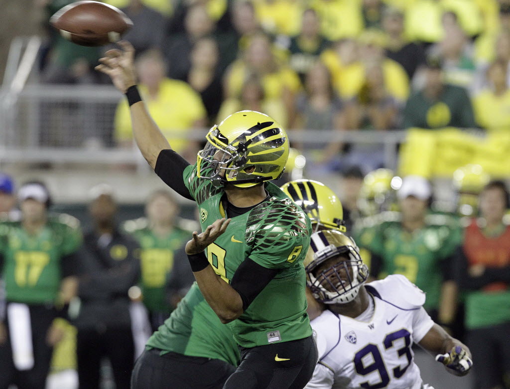 Oregon quarterback Marcus Mariota, left, unleashes a pass as Washington defender Andrew Hudson closes in as the teams play in 2012.