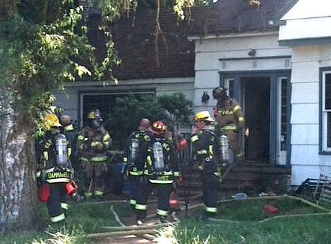 Firefighters work outside a house on the 14100 block of Northeast 72nd Avenue that caught fire on Saturday.