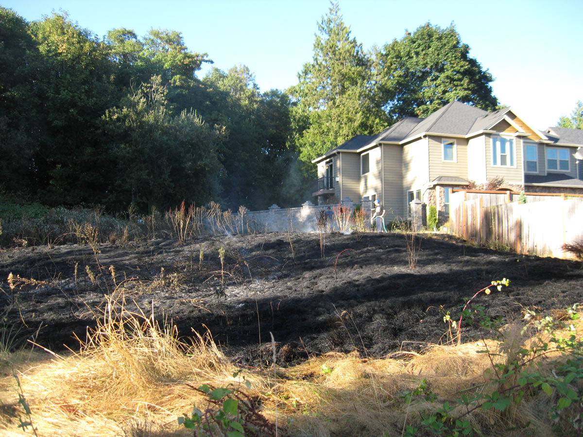 Firefighters mop up a  fire that burned a 100 foot by 100 foot area of grass in the 10300 block of Southeast French Road in Vancouver.