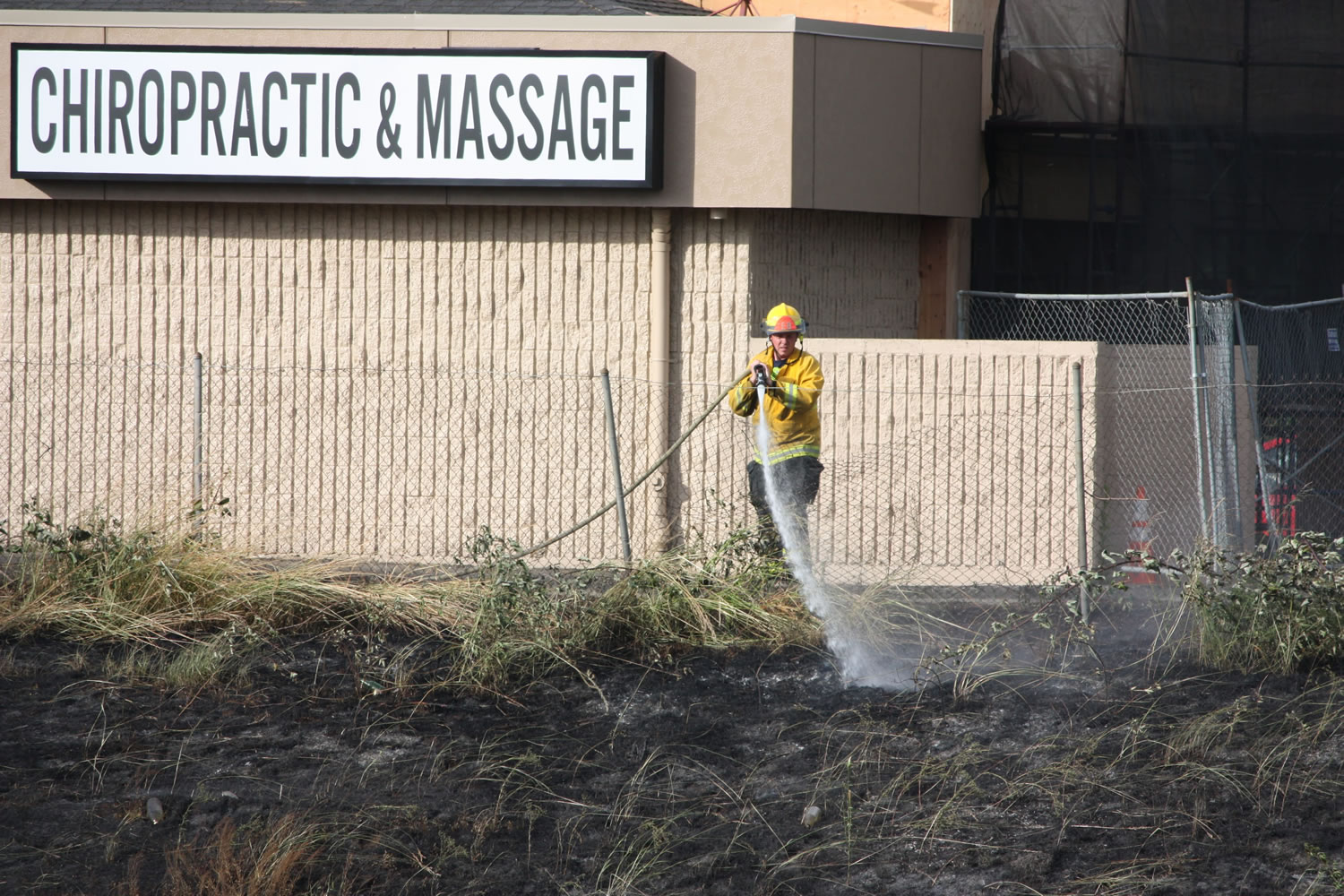 A fire in the grass beside Interstate 205 on Tuesday, June 18, reached the top of the bank and neared shops south of the Fred Meyer at Mill Plain Boulevard and Chkalov Drive.