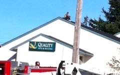 A man sits on the roof of the Quality Inn, 7001 N.E. Highway 99 in Hazel Dell, on Saturday during a fire at the business.