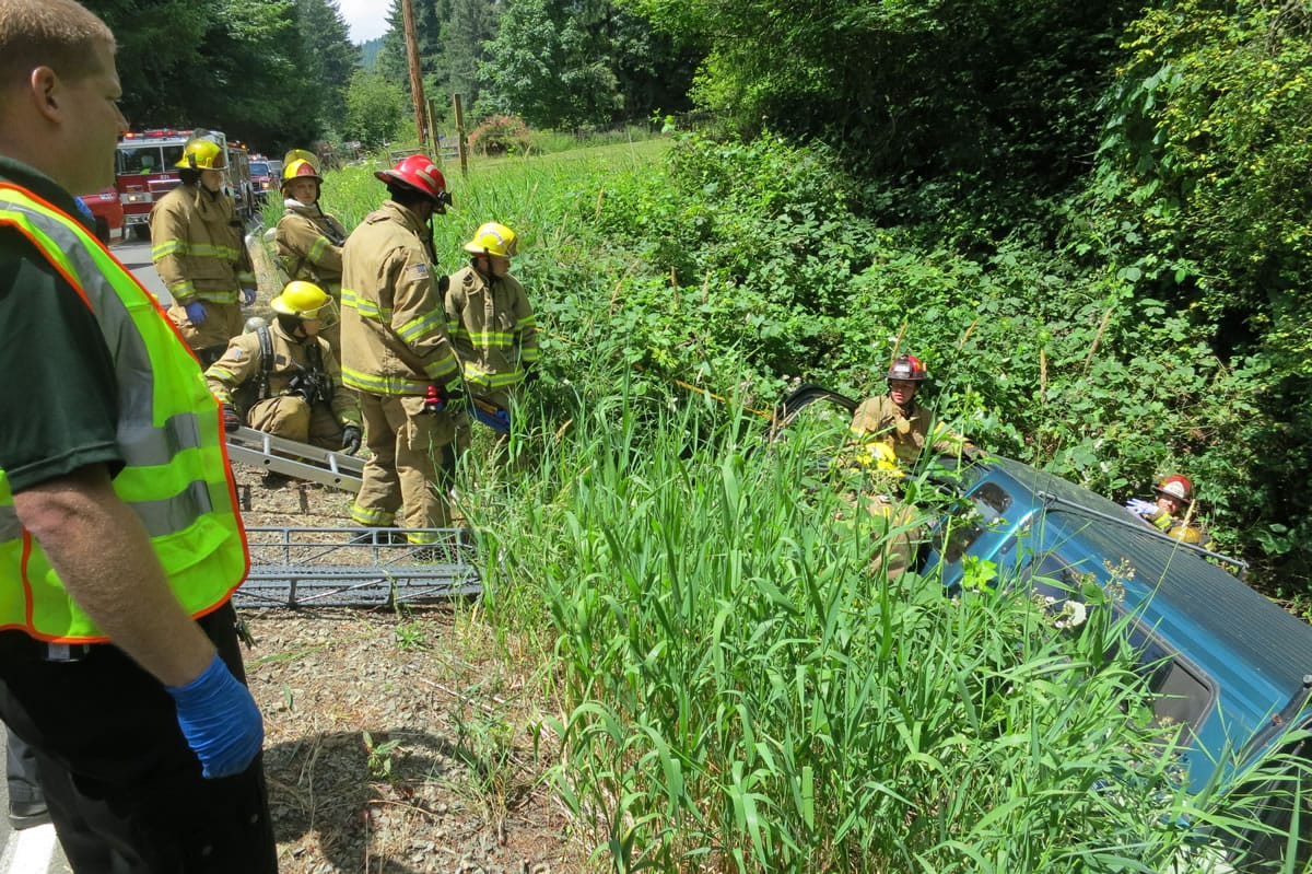 Fire crews work to remove an injured occupant of a pickup that went off Lucia Falls Road near Yacolt on Saturday.