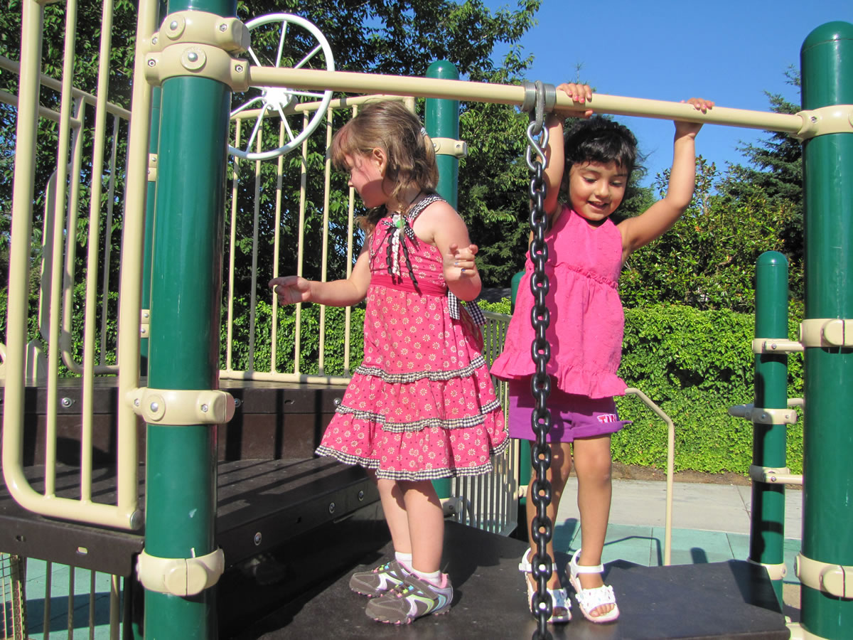Adara Star, left, and Paola Zarate, both 3, share a playful moment Wednesday during a Maplewood neighborhood gathering at MyPark Neighborhood Park in Vancouver.