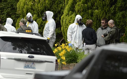 During the execution of a search warrant, members of the Joint Federal Haz-Mat Team, FBI, and local law enforcement gather in front of the Osmun Apartments on Saturday, May 18, 2013 in Spokane. The search warrant is in connection with ricin-laced letters intercepted at a Post Office facility in Spokane earlier in the week.