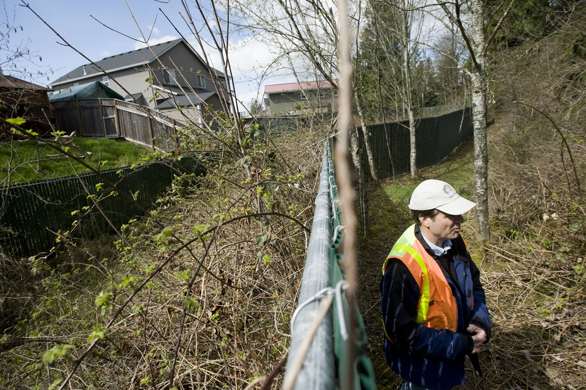 Cary Armstrong, source control specialist with the Clark County Department of Environmental Services, points out a poorly maintained stormwater site in a Vancouver neighborhood in 2011.