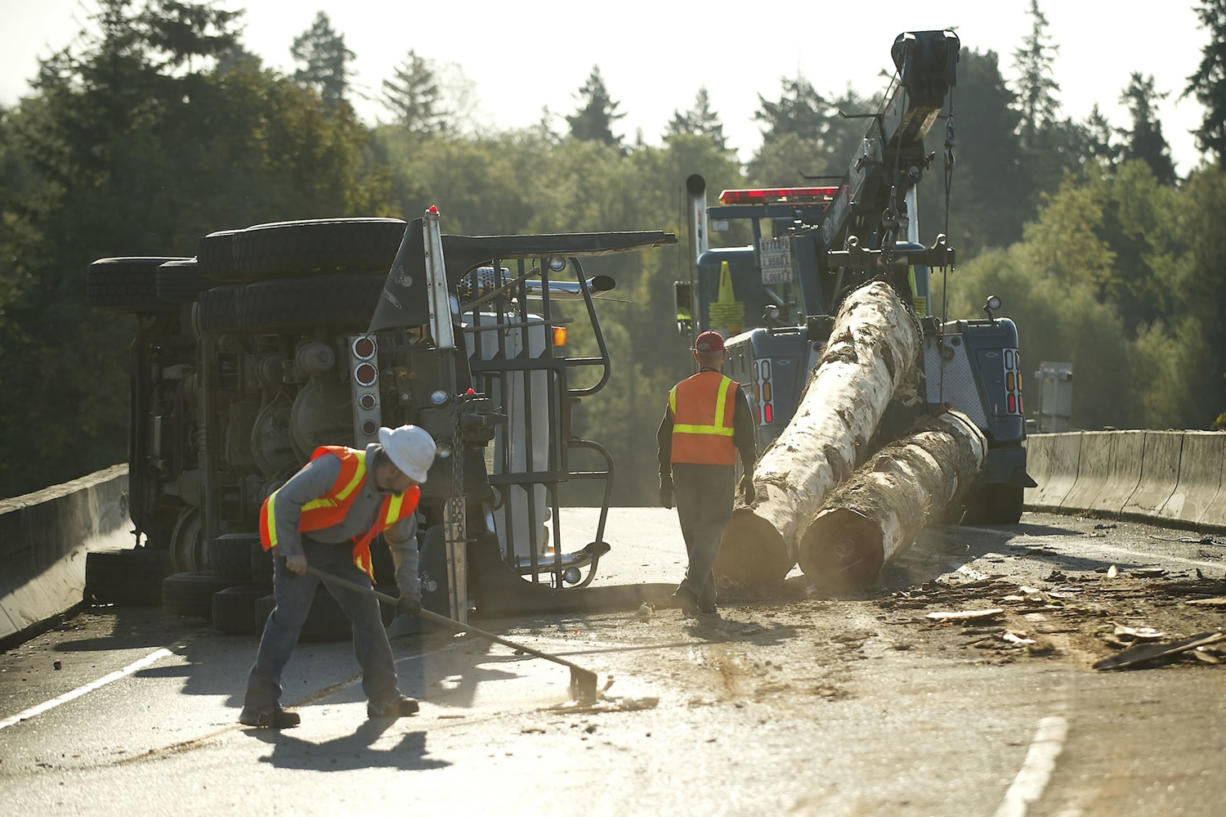 Washington State Department of Transportation workers and tow crews use heavy equipment to remove logs from an overturned log truck on an onramp Wednesday September 12, 2012 in Vancouver, Washington.