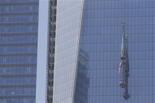 The top piece of the 408-foot spire for One World Trade Center is lifted to the top of the building in New York, Thursday, May 2, 2013. A crane has hoisted a U.S. flag covered spire to the top of New York's One World Trade Center, under construction at the site of the Sept. 11 attacks.