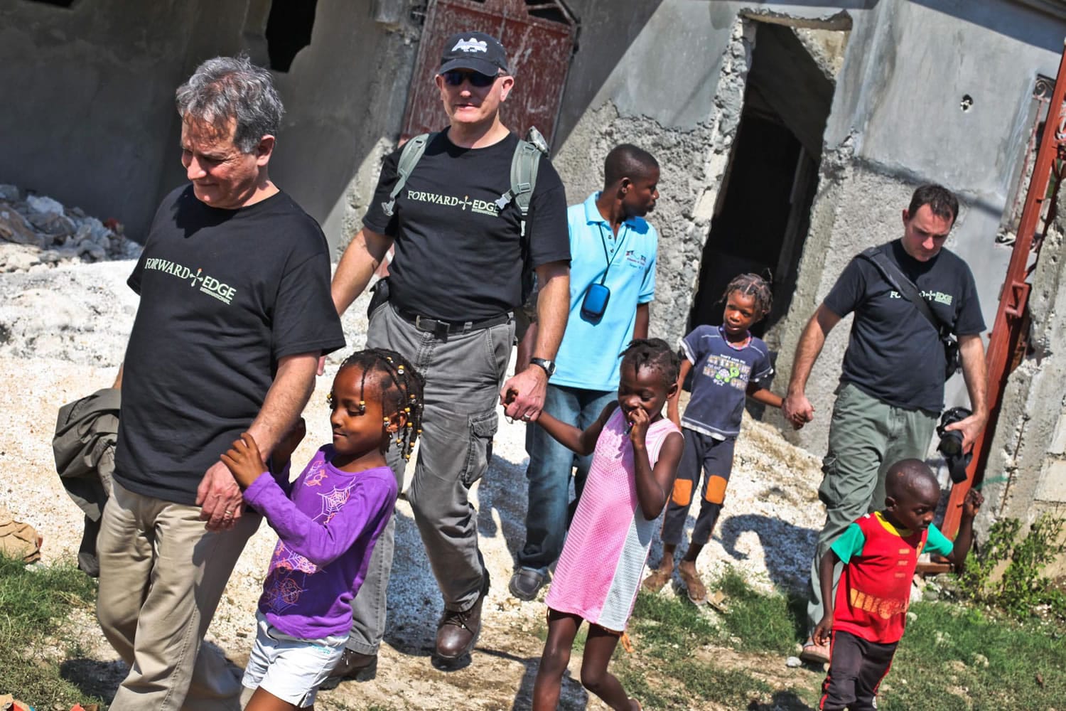 Joe Anfuso, from left, and Forward Edge International team members Nick Rogers and Bob Craddock walk with a group of children during a 2010 mission trip to Port-au-Prince.