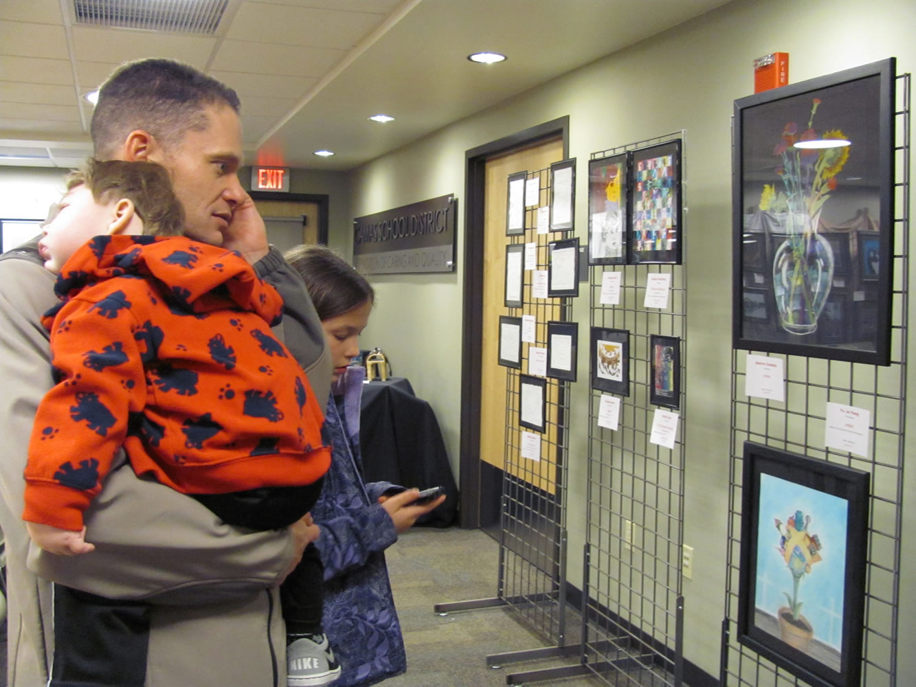 Jeff Snell, Camas School District assistant superintendent, listens to students describe their work at the CHS art show via a recording by dialing a specific number associated with each piece.