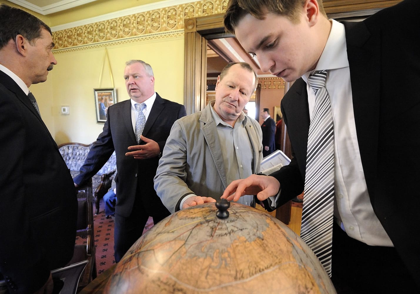 From left, Yuriy Gerasin, Russian consul general based in Seattle, talks to Valery Chkalov while Buck Heidrick of Vancouver and Igor Chkalov (the aviator's great-grandson) look at the 1937 transpolar route on a replica of a globe signed by about 80 explorers and aviators.
