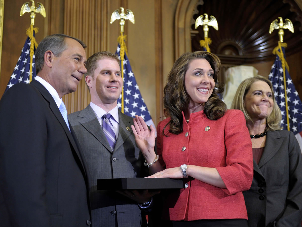 House Speaker John Boehner of Ohio,left, re-enacts the swearing in of Rep. Jaime Herrera Beutler, R-Camas, wearing red, in 2011 on Capitol Hill.