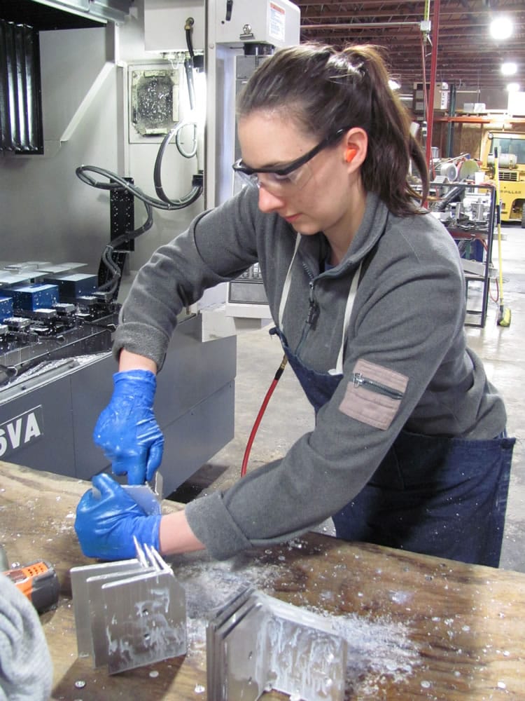 Denise Fretwell, a machinist at Micro Machining LLC, finishes parts that will be machine-dated with the month and year they were manufactured.
