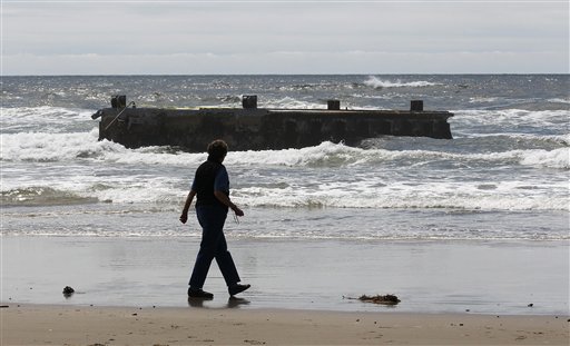 A woman looks at the massive dock that washed ashore on Agate Beach on Wednesdayin Newport, Ore.