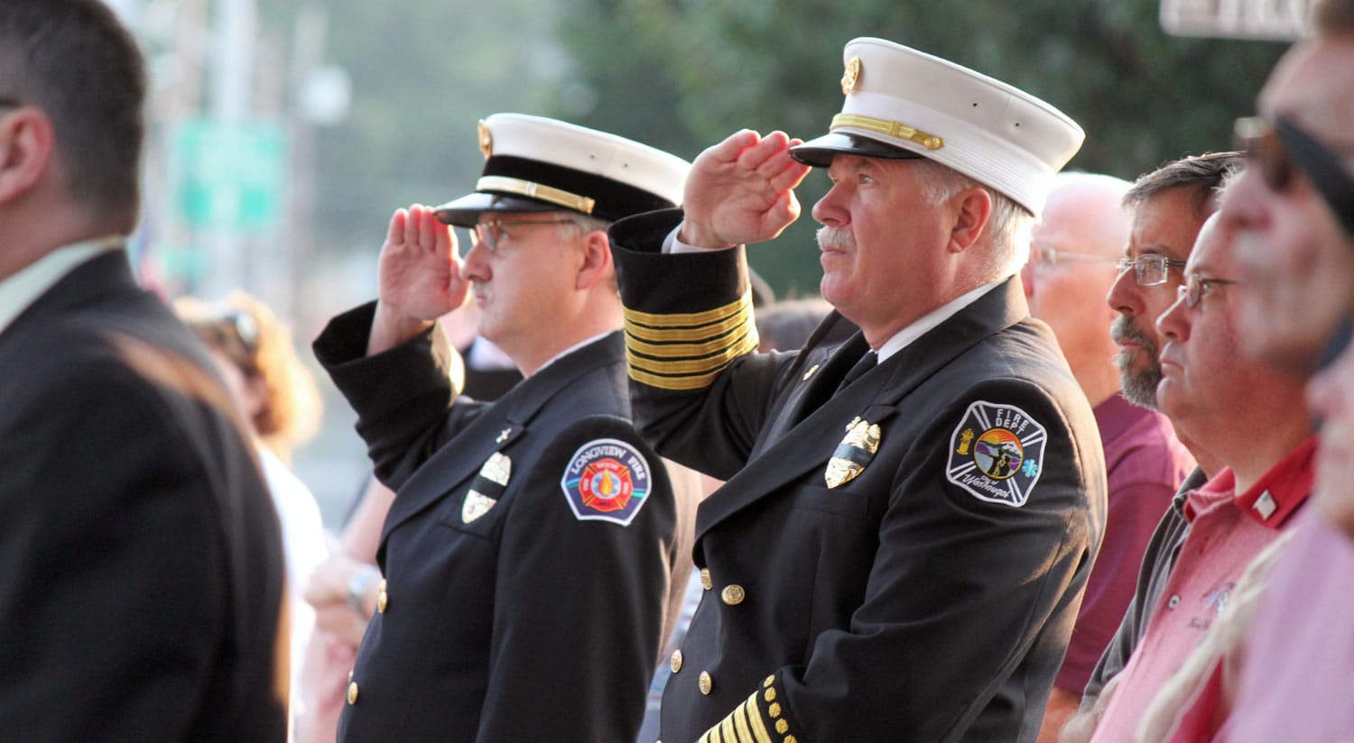 Washougal Fire Chief Ron Schumacher (right) and Longview Battalion Chief Kevin Taylor (left) stand at attention as Camas Battalion Chief Allen Wolk and Camas Fire Capt. Chuck Bettis (not pictured) raise the American flag to half-mast in front of the Camas Public Library Sunday morning, in recognition of the 10-year anniversary of the Sept.