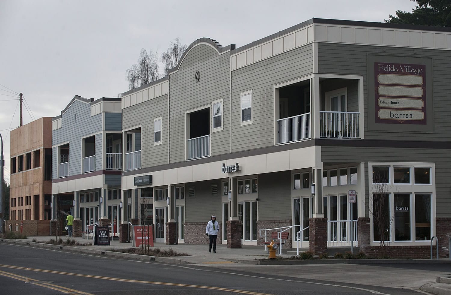 A pedestrian walks past buildings Felida Village, the new development project which includes a mix of commercial and residential space at the corner of Northwest 119th Street and 36th Avenue. Developer Ron Edwards, who lives five blocks from the new buildings, said he hopes the project becomes a gathering place for the community.