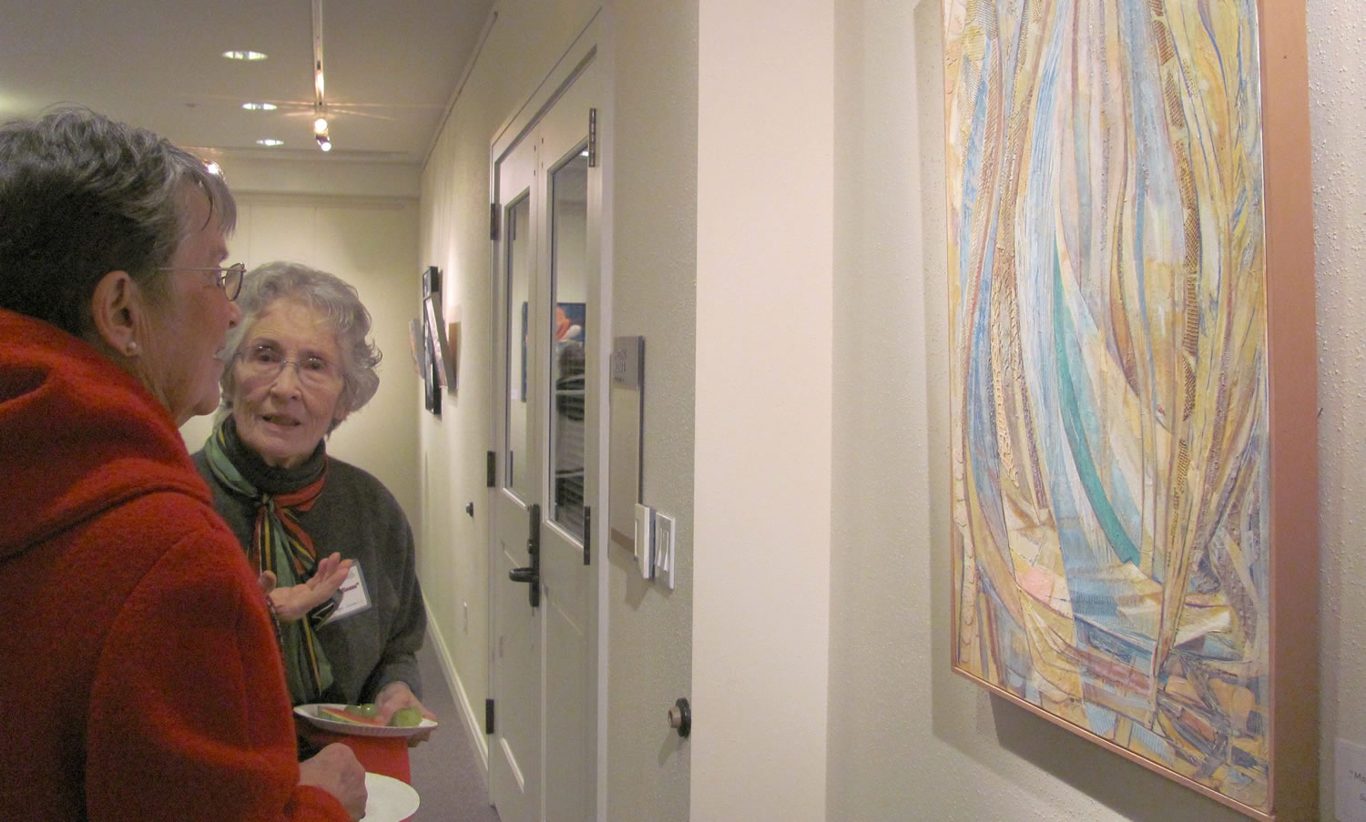 Susan Smith, right, discusses her artwork with an attendee at a First Friday reception.