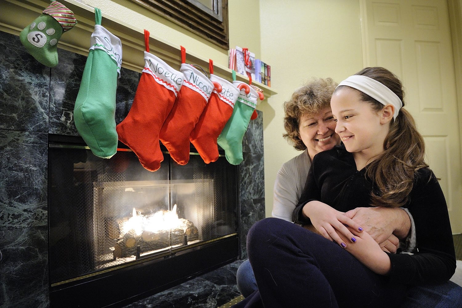 Sandy Scovil, left, holds her youngest daughter, Noelle, 11, in the family's temporary home, a two-bedroom hotel suite. The family was displaced after a fire caused substantial smoke damage to their Felida home on Dec.