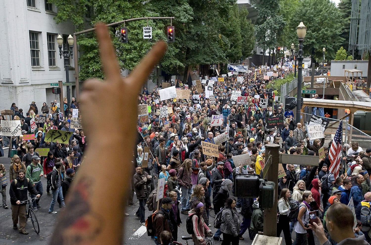 Pam Hogeweide, of Portland, throws up a peace sign, foreground, as protesters march north on SW Second Avenue from SW Jefferson Street in downtown Portland in solidarity with the national protests against wall street bailouts and corporate greed on Thursday October 6, 2011.