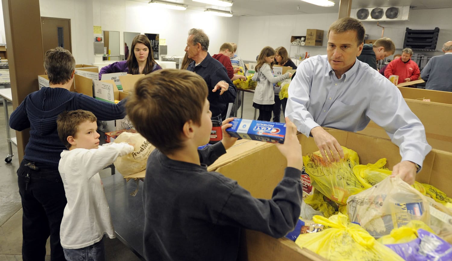 Alan Hamilton, the new executive director of the Clark County Food Bank, works with volunteers from Congregation Kol Ami, including Eli Mitchell-Hopmeier, center, and Zeke Mitchell-Hopmeier, left, as they unpack donations collected during the letter carriers food drive.