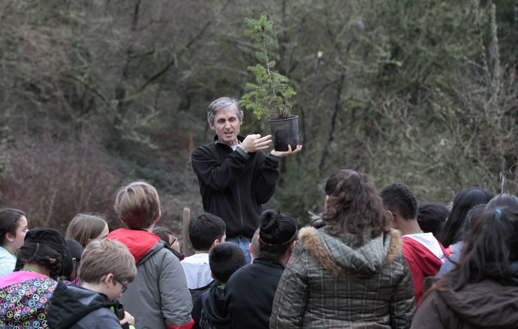 Michael Foster, a volunteer who started Plant for the Planet in Seattle, explains how to plant a Douglas fir seedling at Columbia Springs on Saturday. Sponsored by the United Nations, the event trains children and teens to become Ambassadors for Climate Justice.