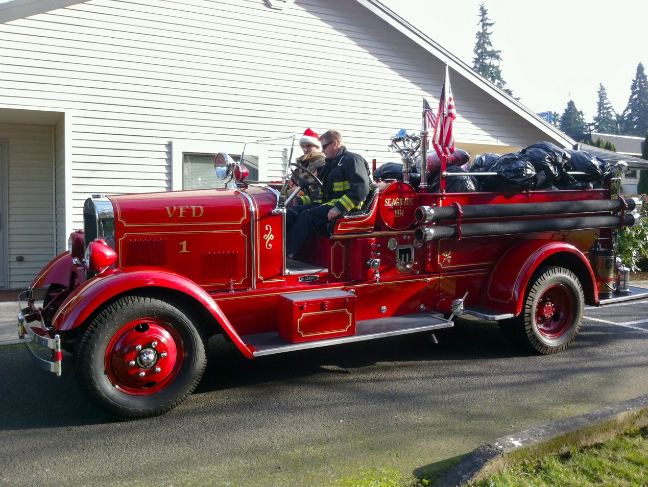 Shumway: Firefighters Scott Branton, driving, and Mike Hamilton deliver coats, blankets and baby food to Open House Ministries on Christmas Eve day in a 1934 fire engine.