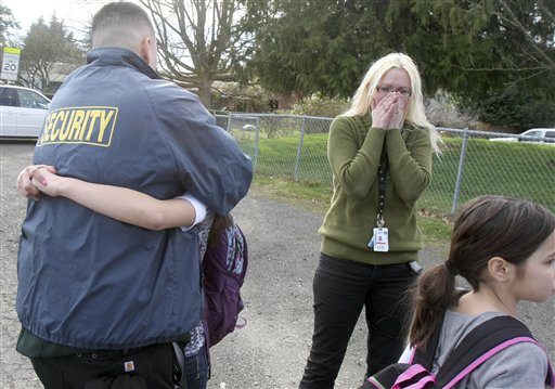 Armin Jahr Elementary School sixth grade student Kiomi Pavlock,12, hugs her dad James outside the school, Wednesday, Feb. 22, 2012, in Bremerton, Wash. They live near a third grade student who was shot inside the school. Behind in the center is friend Misty Allen. Niomi Pavlock,10, right, is a fourth grader, and a close friend of the victim.