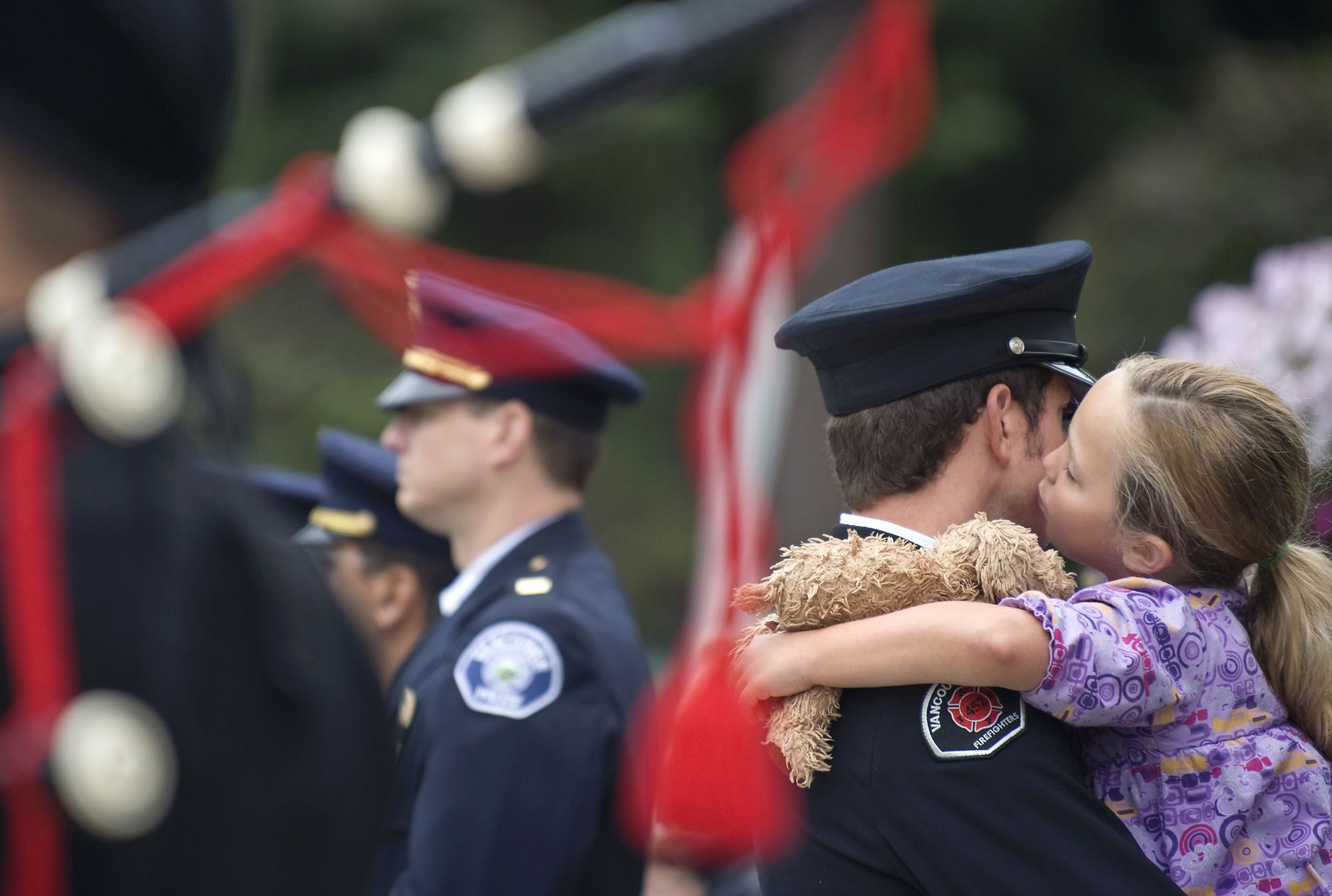 Carsen Yela, 7, of Vancouver, kisses her father, Vancouver firefighter Joe Yela, during a Sept. 11, 2010 flag ceremony to observe the ninth anniversary of Sept. 11, 2001.
