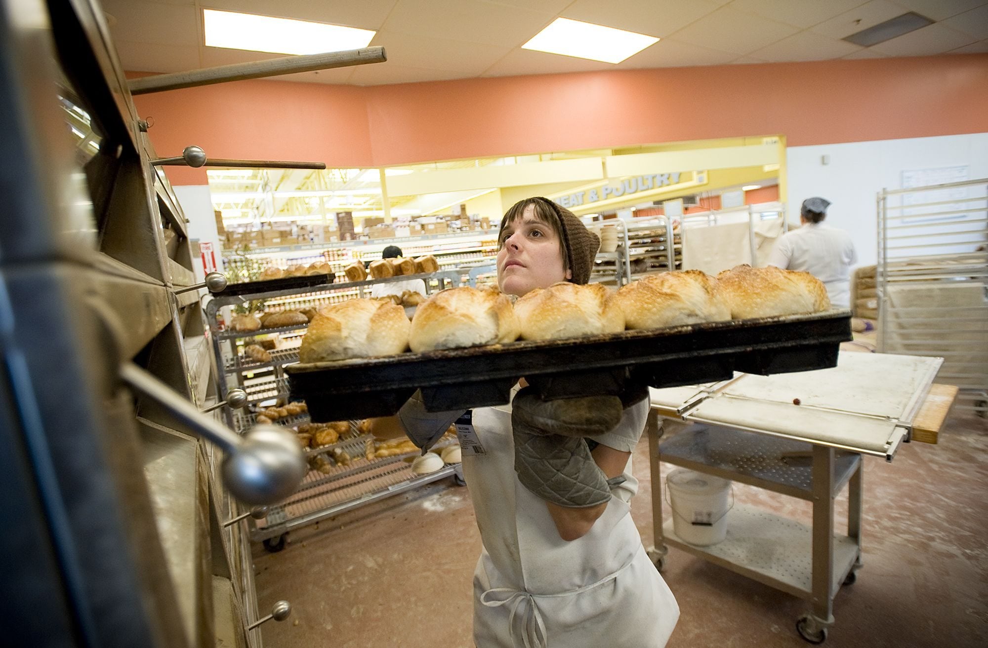 Lauren LaMotte, 30, from Portland, pulls bread from the oven Tuesday at the North Interstate New Seasons in Portland.