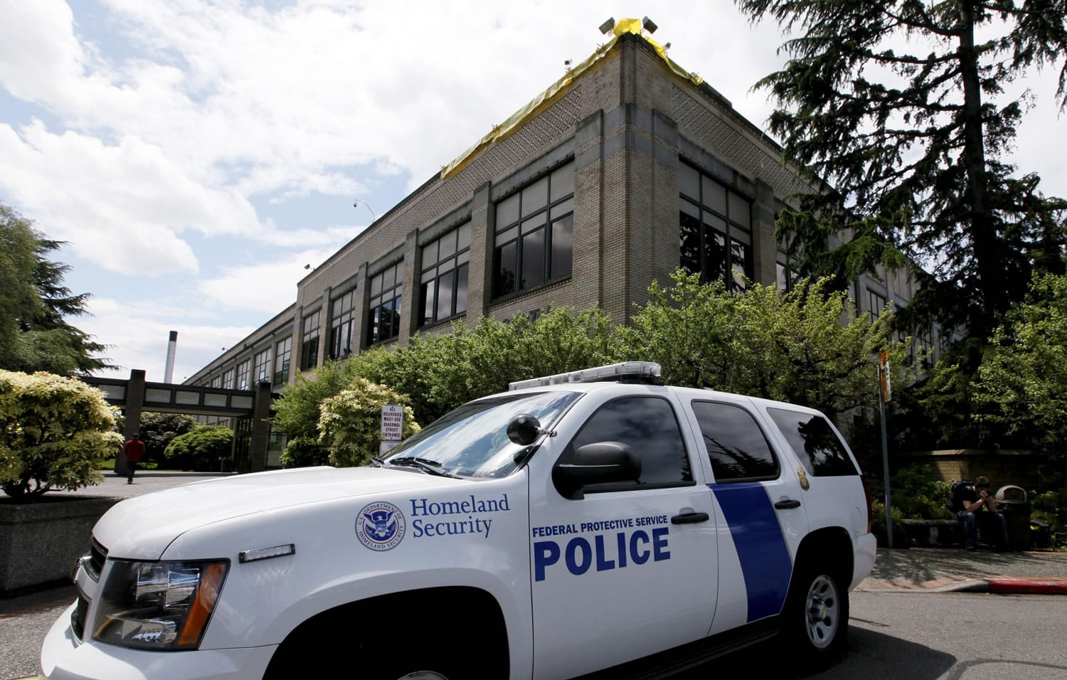 A police vehicle is parked outside a federal building that houses the Seattle Military Processing Center Thursday in Seattle. Two men have been arrested in a plot to use machine guns and grenades in an attack on the military recruiting station there that also houses a day care, the U.S.