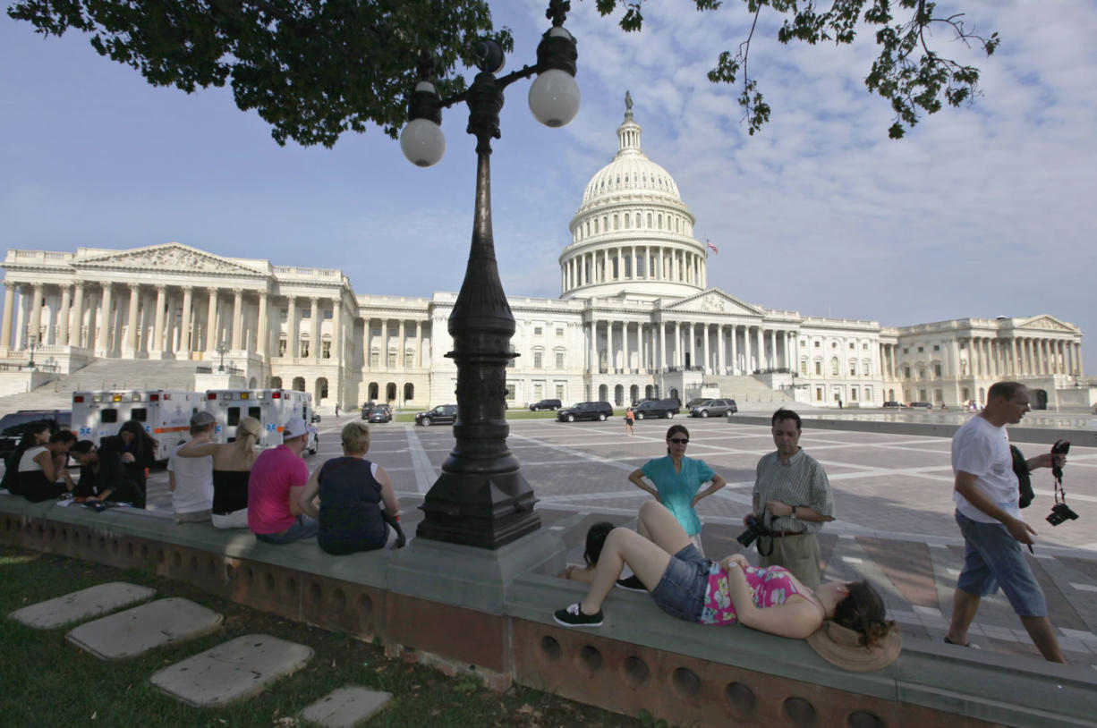 Tourists take a break in the shade on Capitol Hill in Washington Thursday as House Republicans delayed a vote on a newly modified plan to stave off a government default.