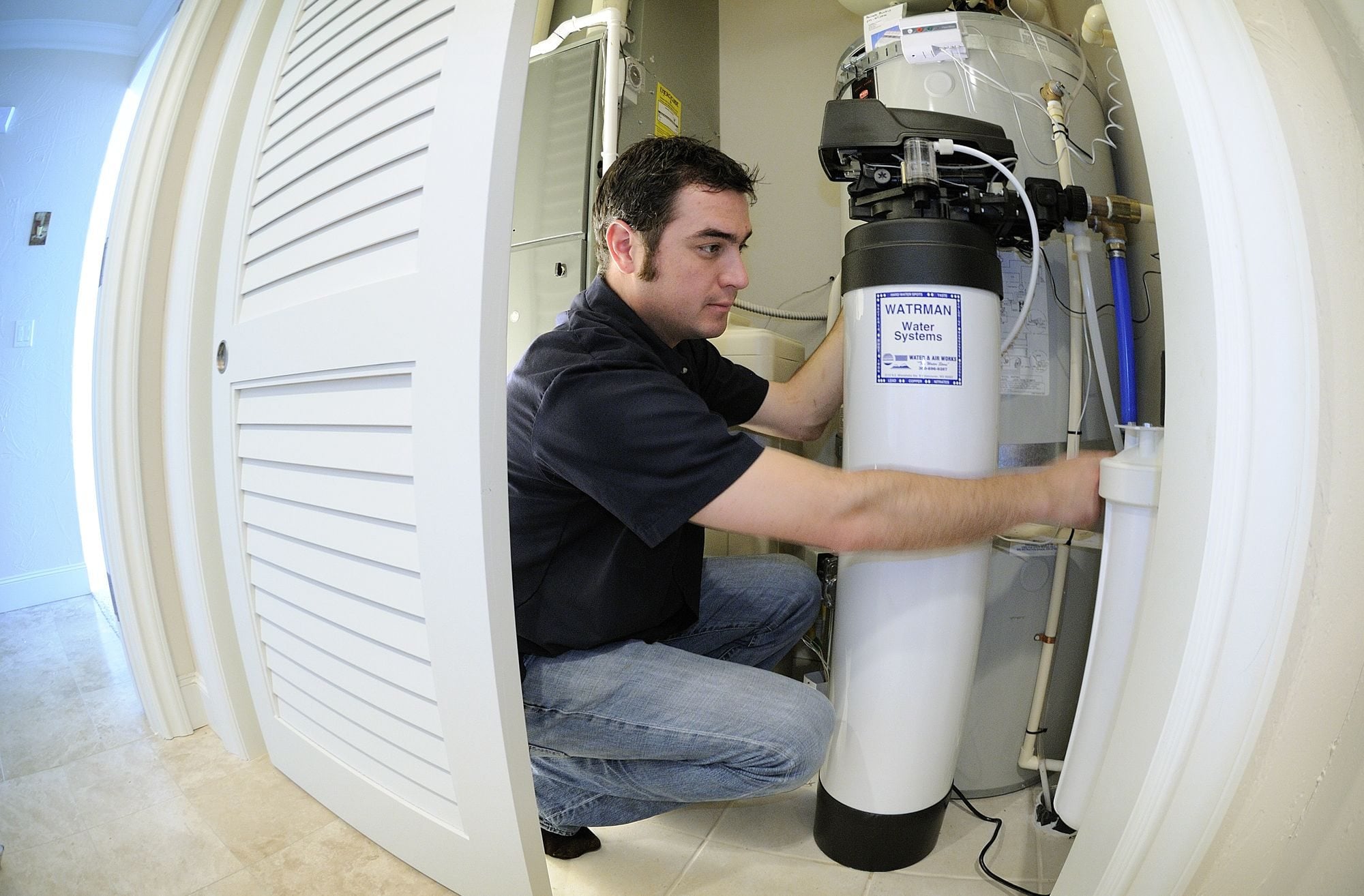 Aron Jacobus installs a water filter softener and does maintenance with water treatment equipment.
