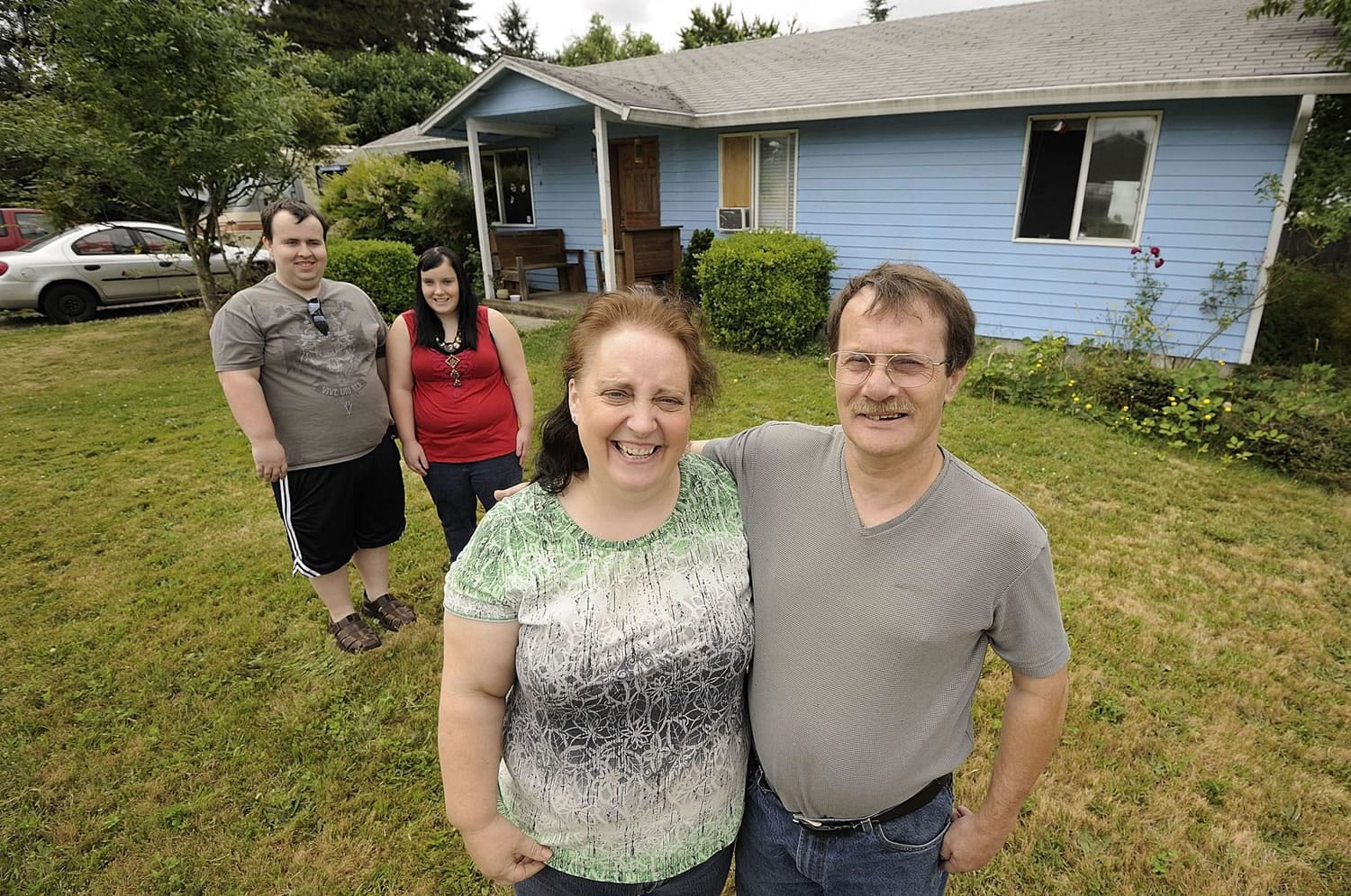 Nearly 20 years after they helped build it, the Johnson family -- from left, Joshua, Elishia, Cindy and Michael -- still live in their sky-blue Evergreen Habitat for Humanity home.