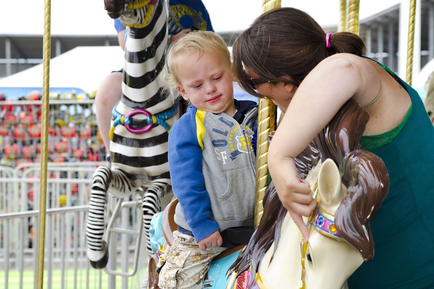 Diana Vick, right, calms her son, Chase, 2, by distracting him with the horse's face before the carousel starts Tuesday at the Clark County Fair.