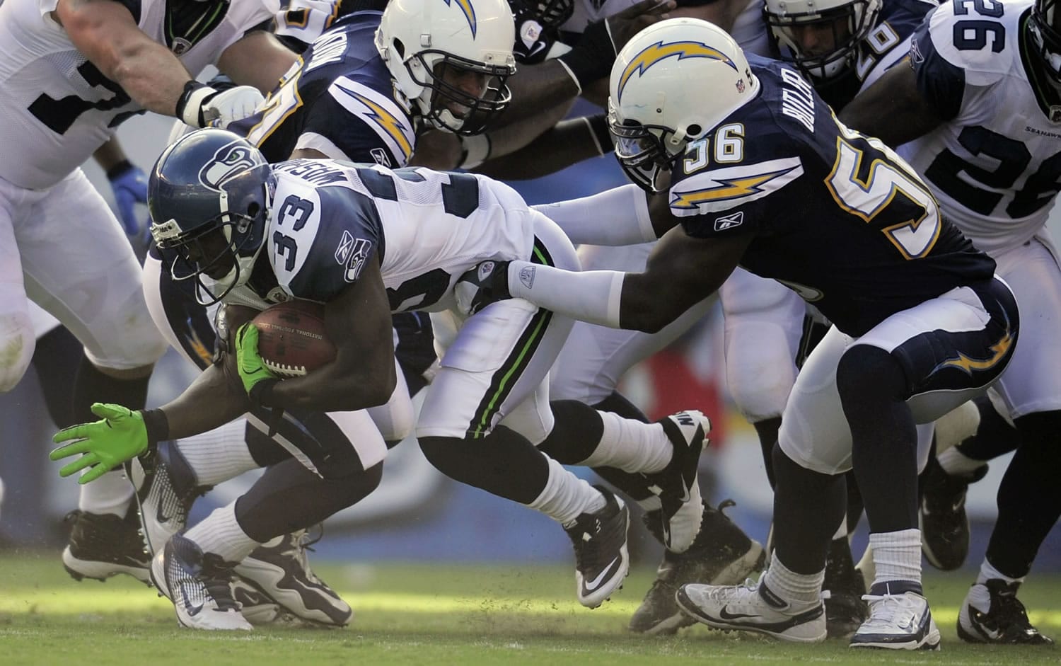 Seattle Seahawks running back Leon Washington (33), left, is held up by San Diego Chargers linebacker Donald Butler during the first half Thursday.