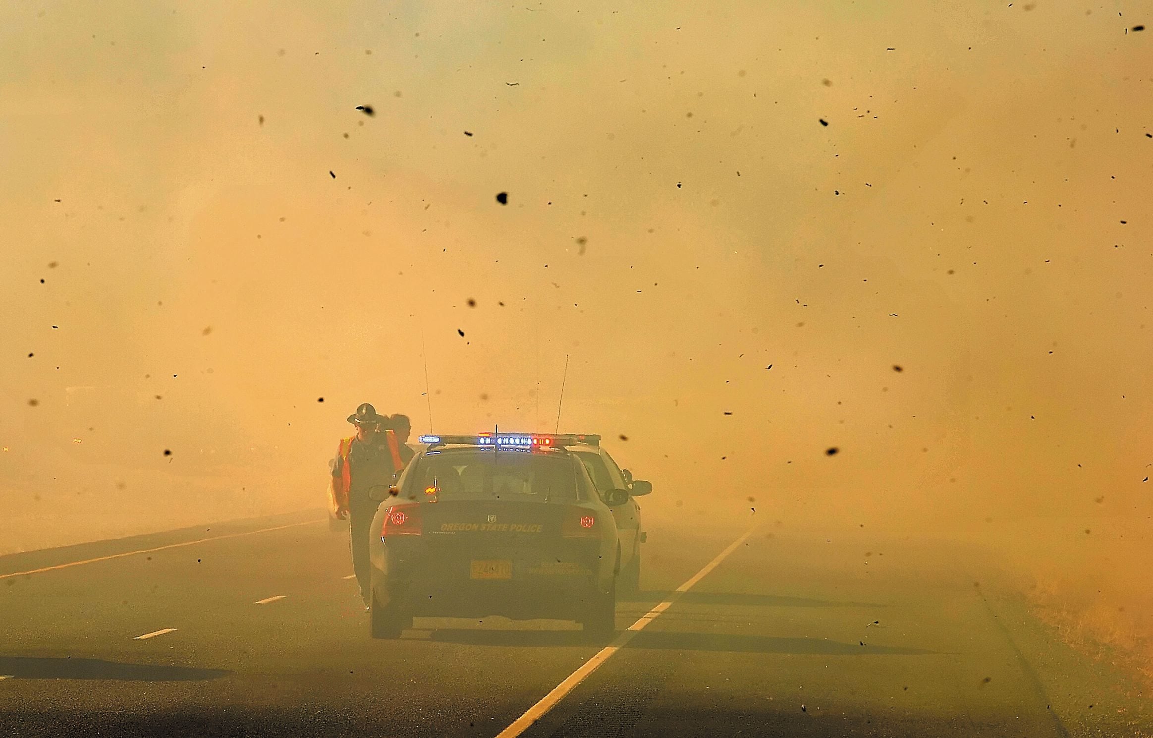 An Oregon State Police trooper dodges ash from a fire burning along Interstate 5 near Rogue River, Ore., on Thursday.