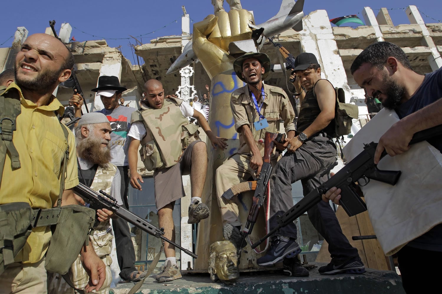 Rebel fighters stomp on the head of a statue of Moammar Gadhafi on Tuesday inside his main compound in Tripoli, Libya.