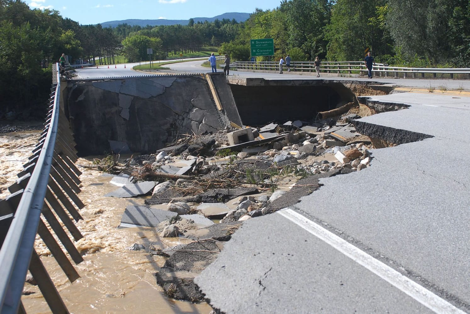 People take photos of a washed-out section of Route 7 south of Rutland, Vt., Monday, following heavy rains from Tropical Storm Irene that swelled rivers the day before.