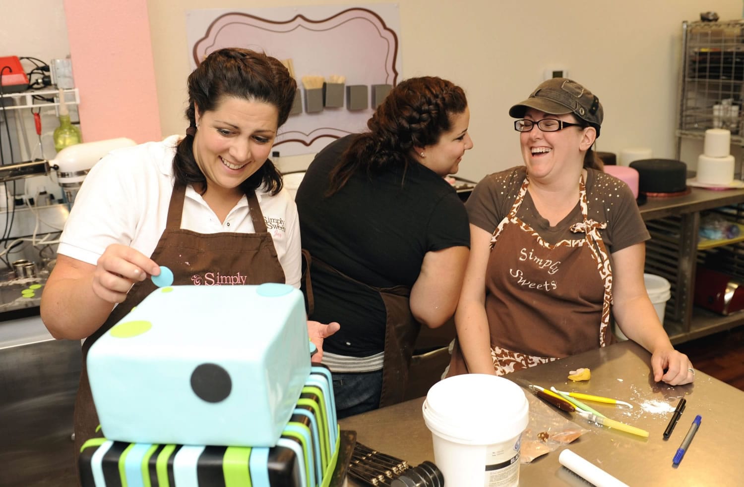 Simply Sweets' owner Jen Allpress, left, works on a birthday cake with store manager Lisa Dachsel, center, and Helen Malone.