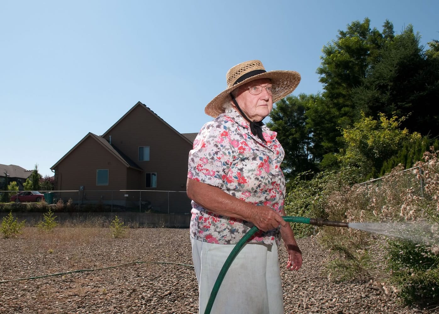 Julia Spellman, 87, hoses down thistle in a bioswale by her home near Prairie High School recently.