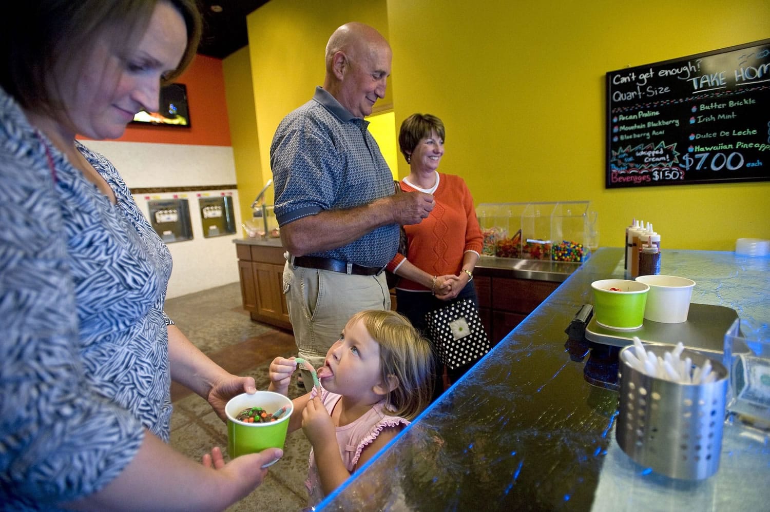 Natalie Shumaker, 4, tastes a gummy worm while her mother, Katy Shumaker, holds her cup of frozen yogurt and grandparents Tom and Liz Shumaker pay in the background at Yo 2 Go frozen yogurt shop Wednesday in Vancouver.