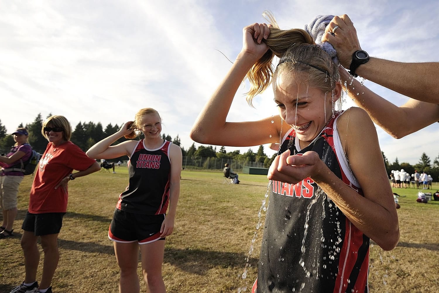 Union freshman Alexis Fuller gets a cold splash of water on her back before running a varsity race at a meet at Skyview High School.