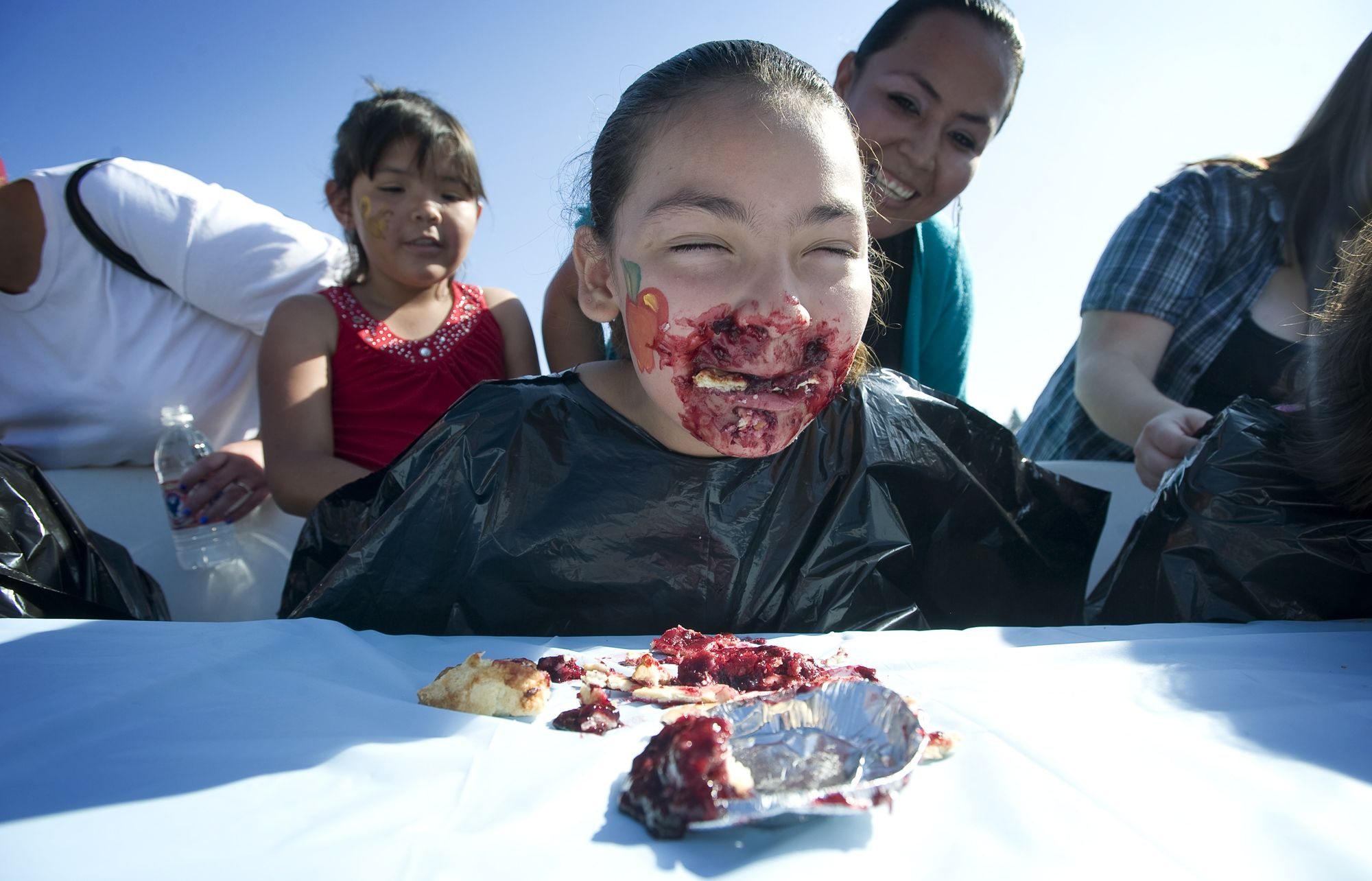 Jayleene Arellano, 10, of Vancouver, competes in a pie-eating contest Saturday at the Harvest Fun Day at Heritage Farm in Hazel Dell. Her mother, Olivia Arellano, and sister Aaliyah, 8, cheer her on.
